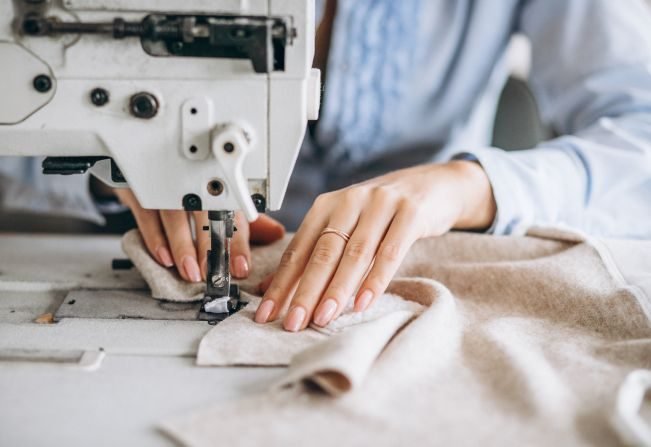 Costureira costurando peça em máquina industrial